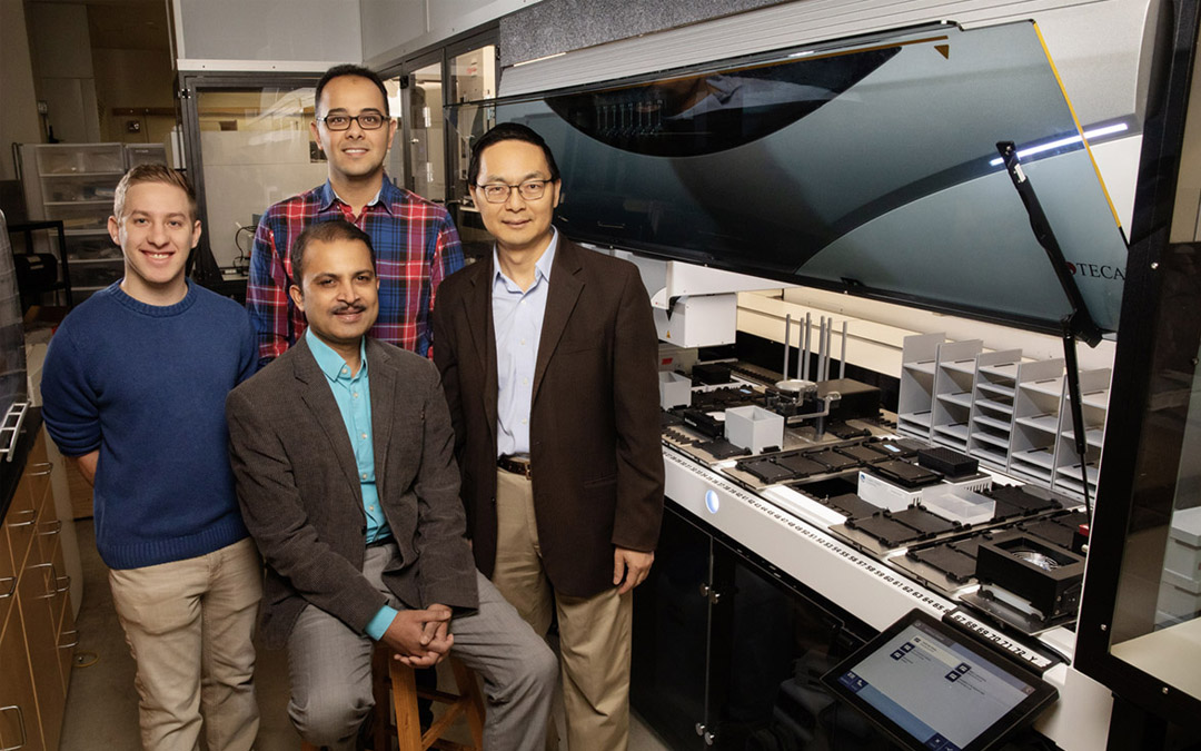 Scott Weisberg, left, professor Saurabh Sinha, seated, Mohammad (Sam) Hamedi Rad and professor Huimin Zhao have combined a fully automated robotic platform with artificial intelligence to develop a new way to manufacture chemicals.