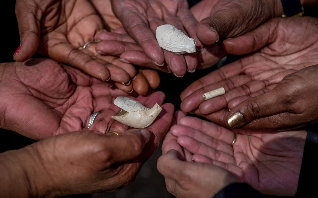 Descendants of people believed to have been enslaved in Crownsville, Md., hold pieces of clay pipes that archaeologist Julie Schablitsky found on the site of a former slave cabin.