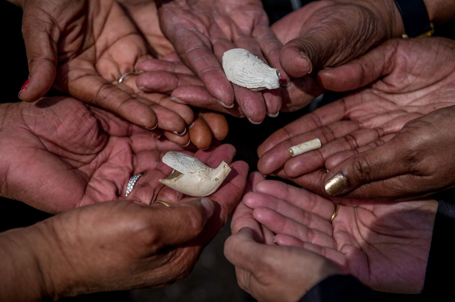 Descendants of people believed to have been enslaved in Crownsville, Md., hold pieces of clay pipes that archaeologist Julie Schablitsky found on the site of a former slave cabin. (Mary F. Calvert/For The Washington Post)